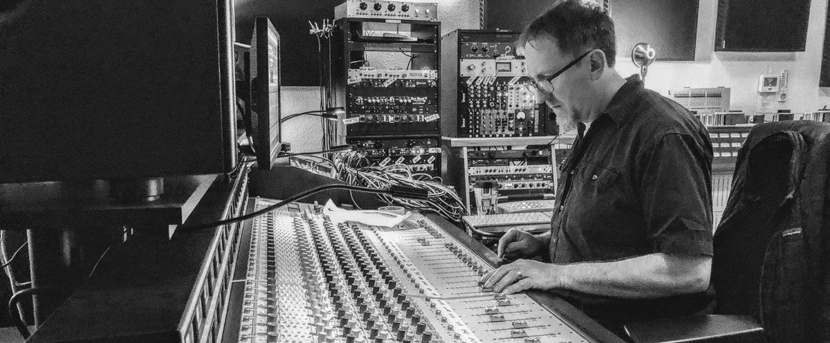 Matt Boudreau working at the console at Jackpot in Portland, racks of outboard gear behind him.