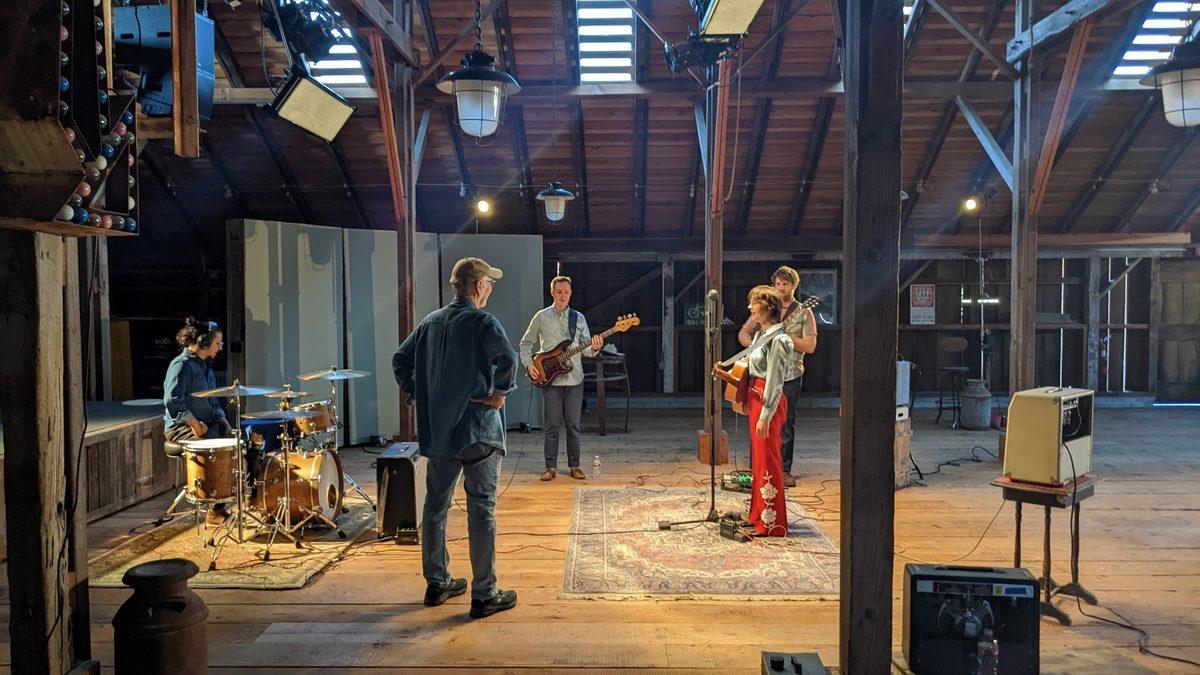 A band set up to record live on the floor of a big wooden barn.